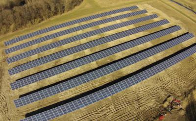 Fotoet viser et luftfoto af en stor solcellepark placeret på et åbent areal